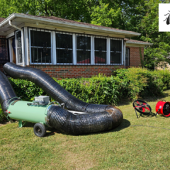 Professional bed bug heat treatment setup outside a brick home, featuring a propane-fired heater, large mylar ductwork running into the house, and propane tanks on the lawn