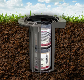 Photo showing a cut away of a Trelona ATBS termite bait station placed in the ground for termite protection.